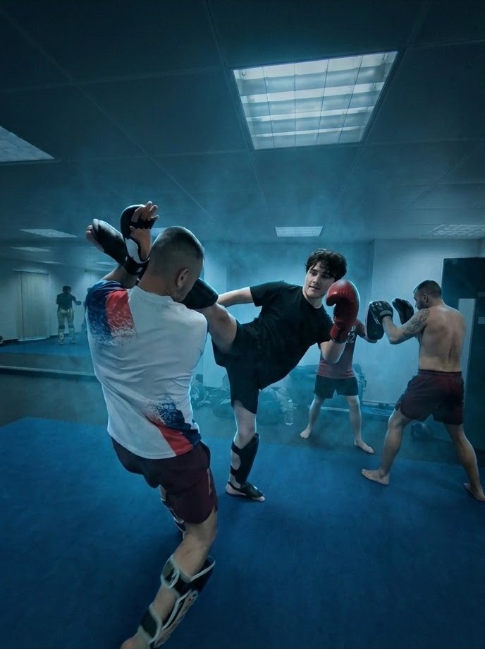 Head kick onto a pad in the blue-lit training room