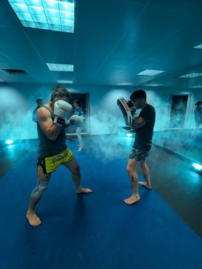 Boxer in guard facing pads through teal haze