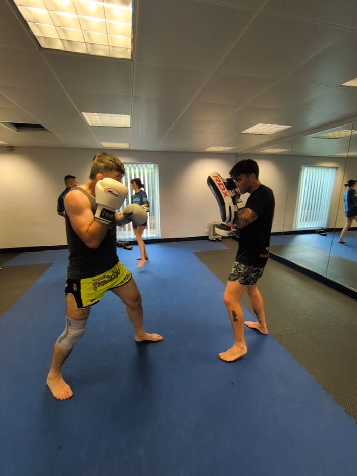 Boxer in guard facing a pad holder