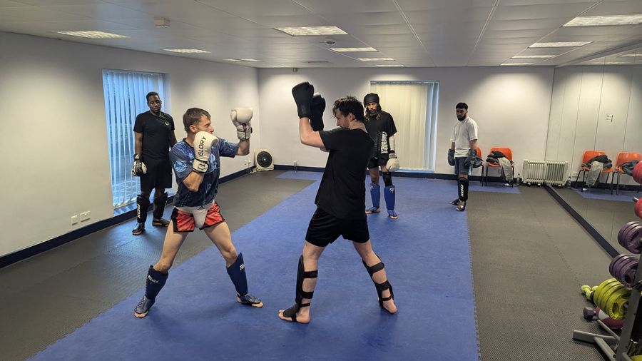 Two members sparring with others watching