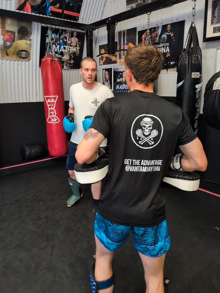 Coach holding pads in a Vanta skull T-shirt